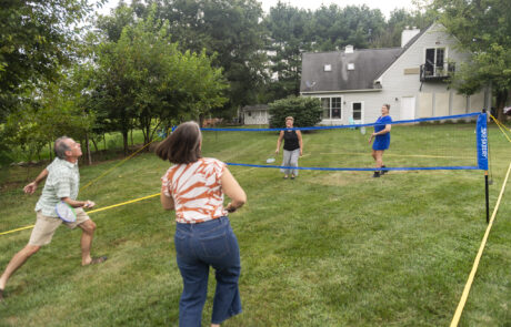 People playing badminton in the yard by the pool